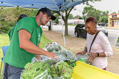 Good Life Growing volunteer Matt Stoyanov helps Caroline Moore pick out produce at the group’s weekly produce stand. Through the Healthy Schools Healthy Communities initiative, BJC School Outreach and Youth Development, St. Louis Public Schools and the Missouri Foundation for Health are working with Good Life Growing to address the lack of access to fresh food in St. Louis neighborhoods. The groups have established a weekly produce stand that provides access to fresh vegetables and fruits year-round. 